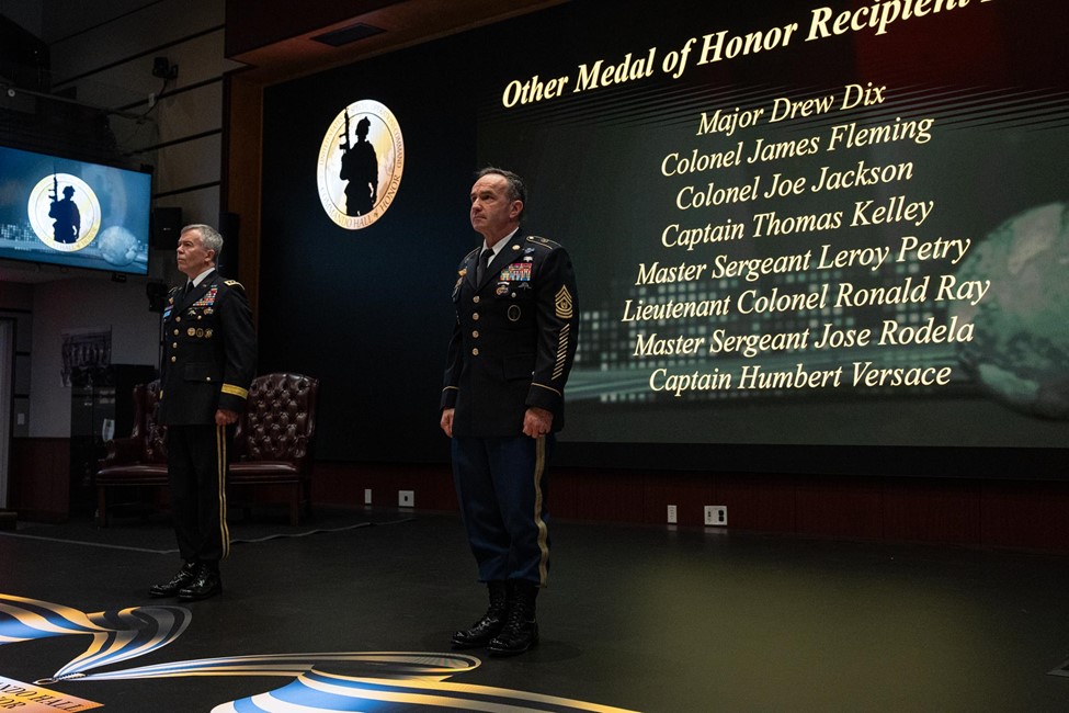 General Fenton and Sergeant Major Shorter standing at attention in front of a screen showing a list of Medal of Honor recipients