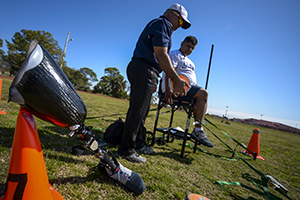 Richard Roberts, seated throws coach, gives directions on how to throw a discus to U.S. Army Staff Sgt. (Ret.) Roy Rodriguez, a 